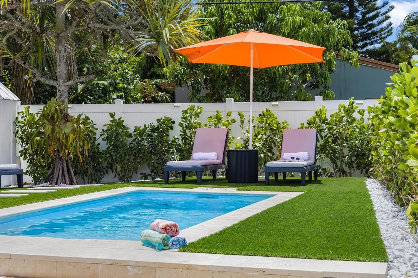 Poolside lounge chairs and orange umbrella beside the heated pool at Casa Palma in Fort Lauderdale