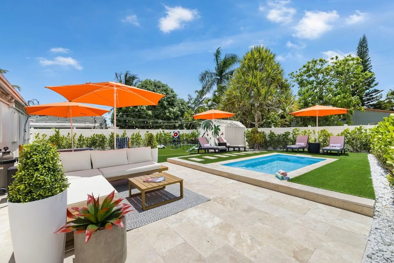 Private heated pool with orange umbrellas and lounge seating at Casa Palma vacation rental in Fort Lauderdale